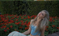 a young woman sitting on a bench in front of flowers