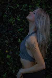 a woman in a gray top with a tattoo on her arm